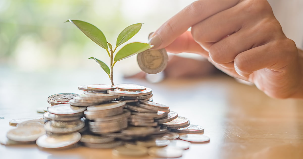 Plante qui pousse dans une pile de pièces. Et une main qui ajoute une pièce à la pile