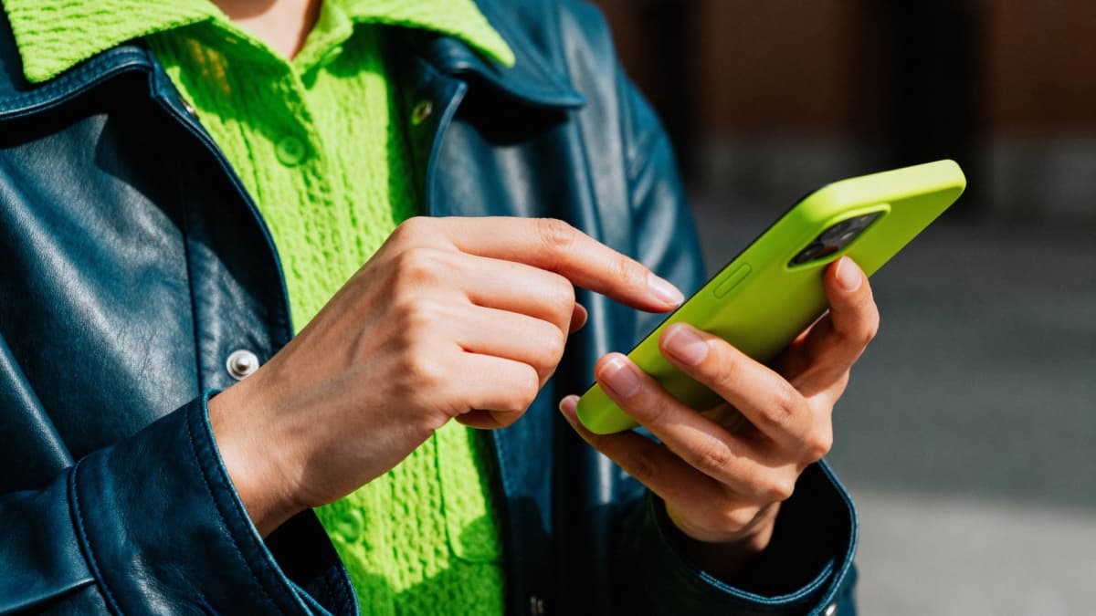 Femme sur son smartphone avec une coque verte.