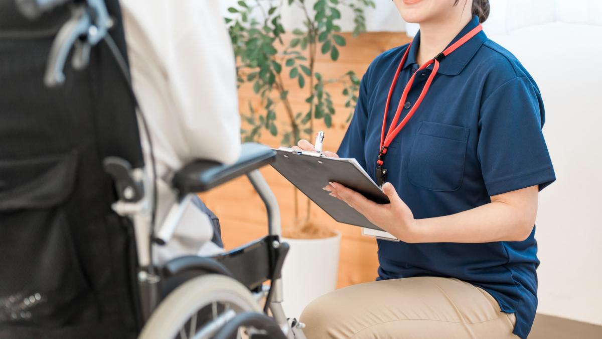 Une ergothérapeute qui prend en charge un patient en chaise roulante.