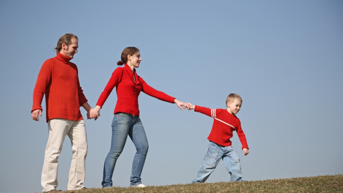 Famille avec pulls rouge marchant à la campagne.