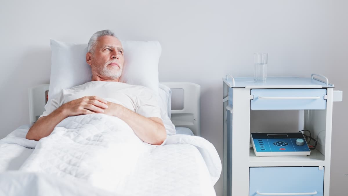 Homme allongé sur un lit d'hôpital.