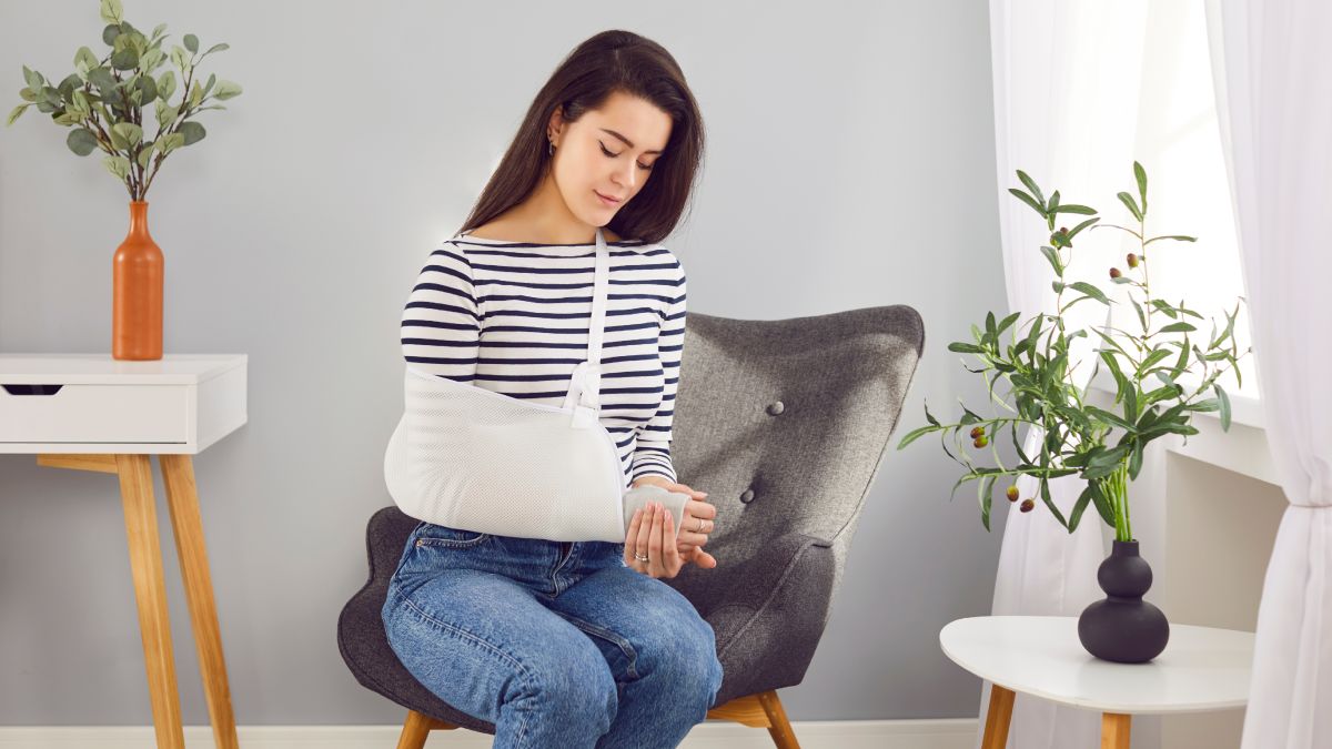 Jeune femme blessée assise sur une chaise chez elle.