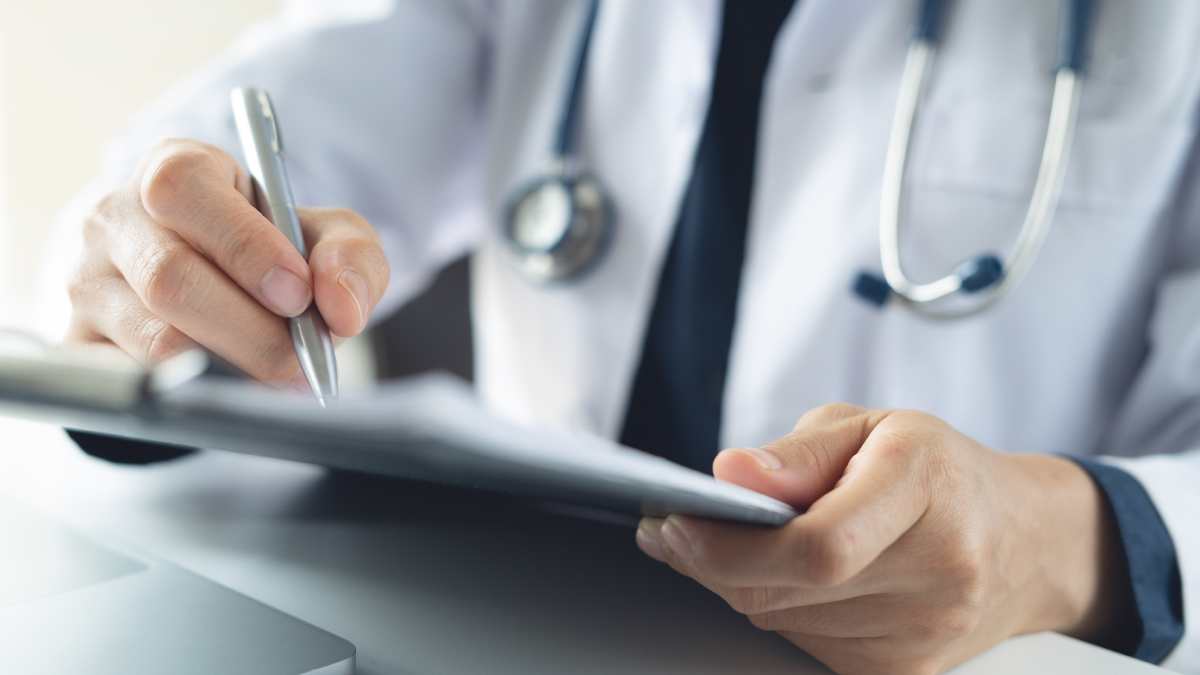 Médecin qui prend des notes sur un carnet.