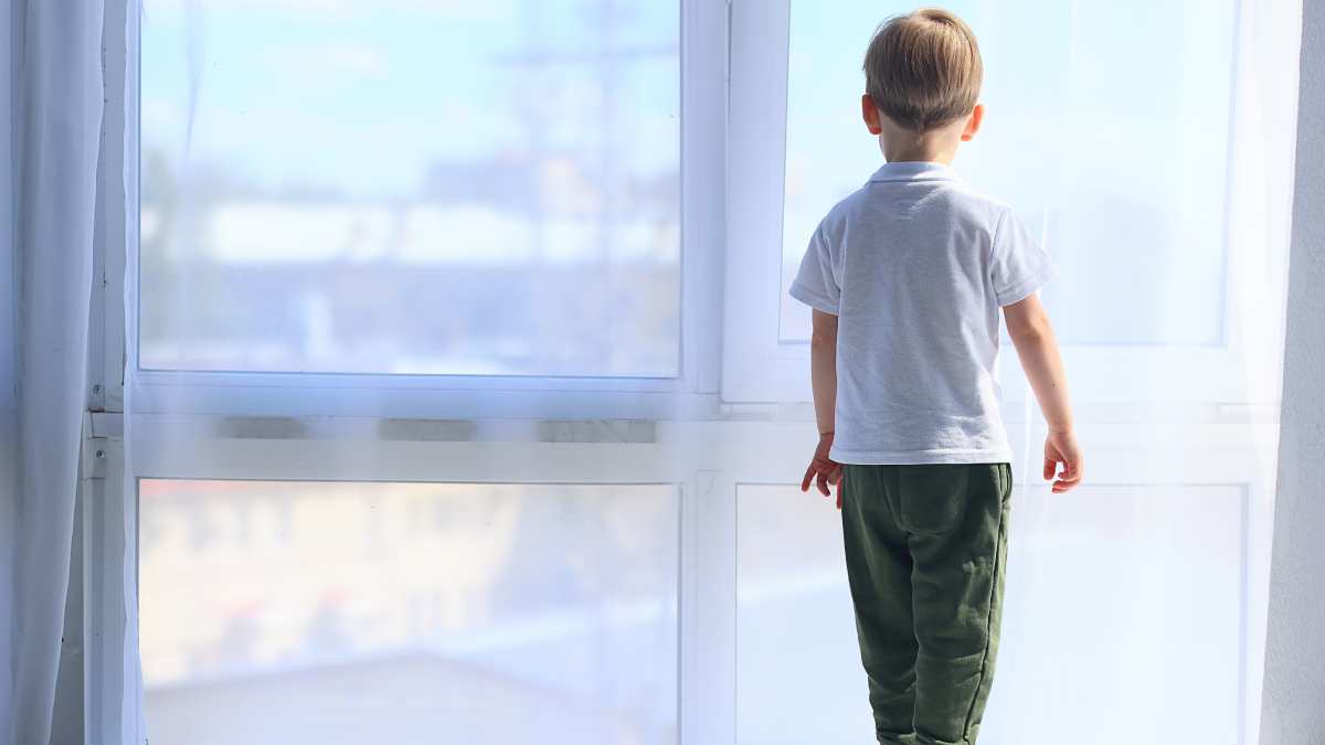 Petit garçon de 6 ans regardant par la fenêtre.