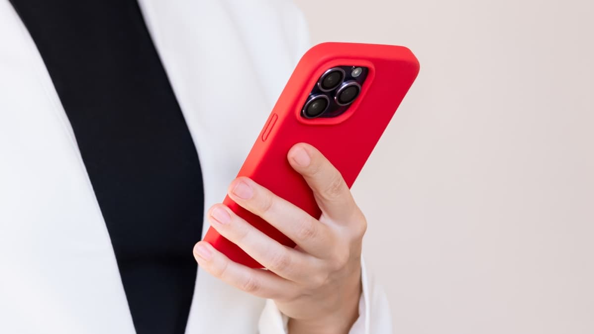 Femme tenant en main un smartphone avec une coque rouge.