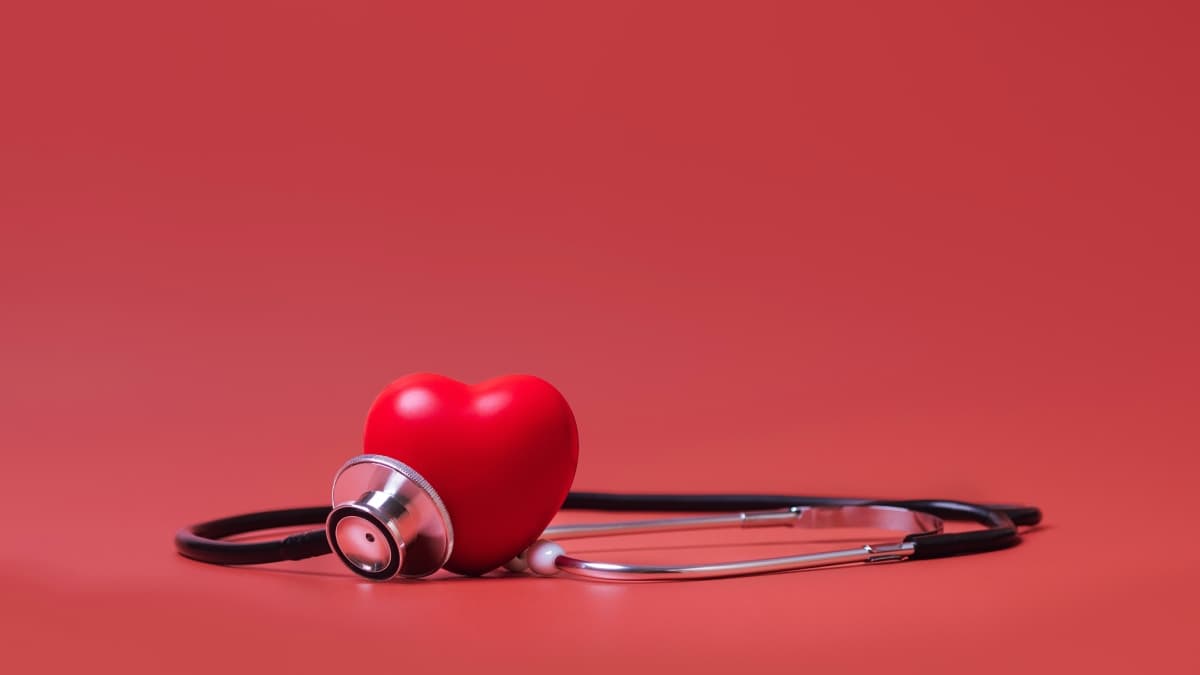 Stéthoscope sur fond rouge avec un coeur.