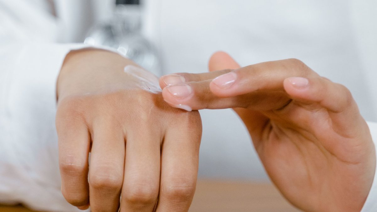 Dermatologue se mettant de la crème sur la main.