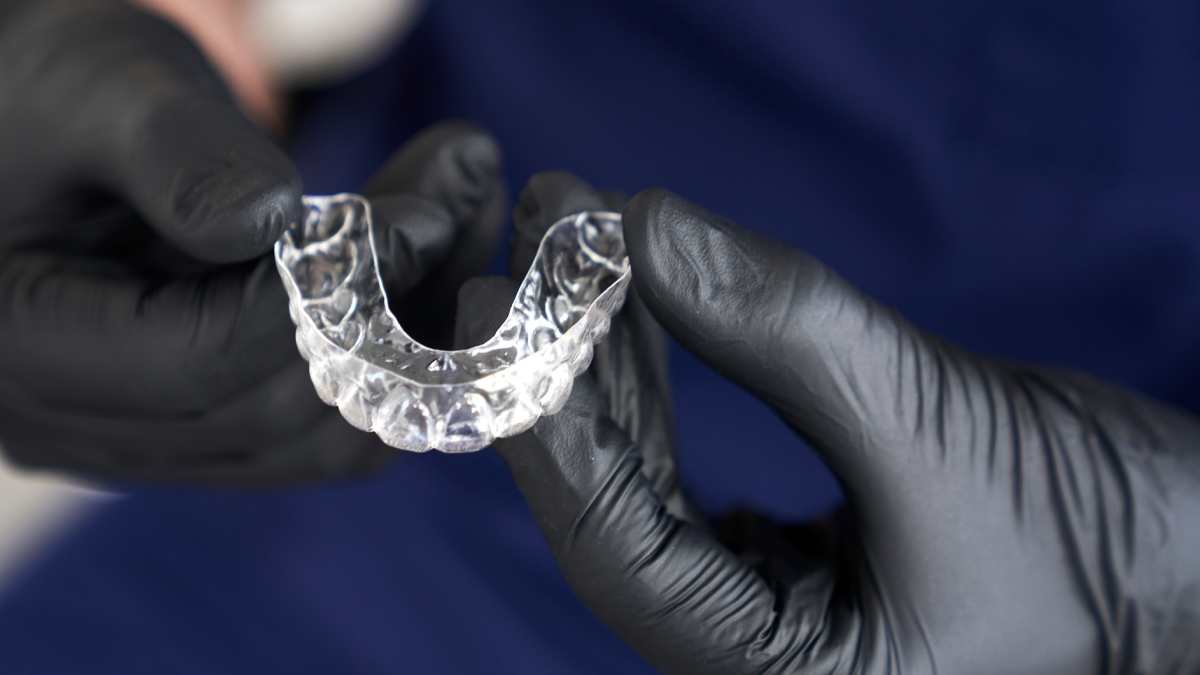 Orthodontiste tenant dans ses mains une gouttière dentaire.