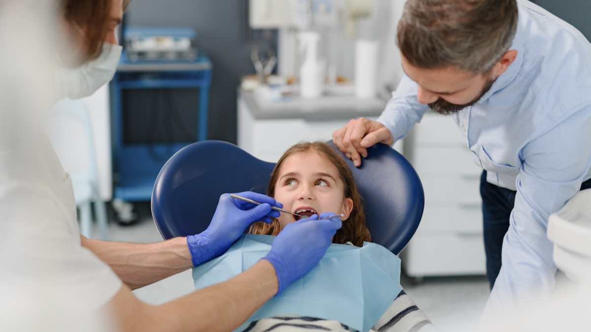une enfant et son père en consultation chez un orthodontiste.