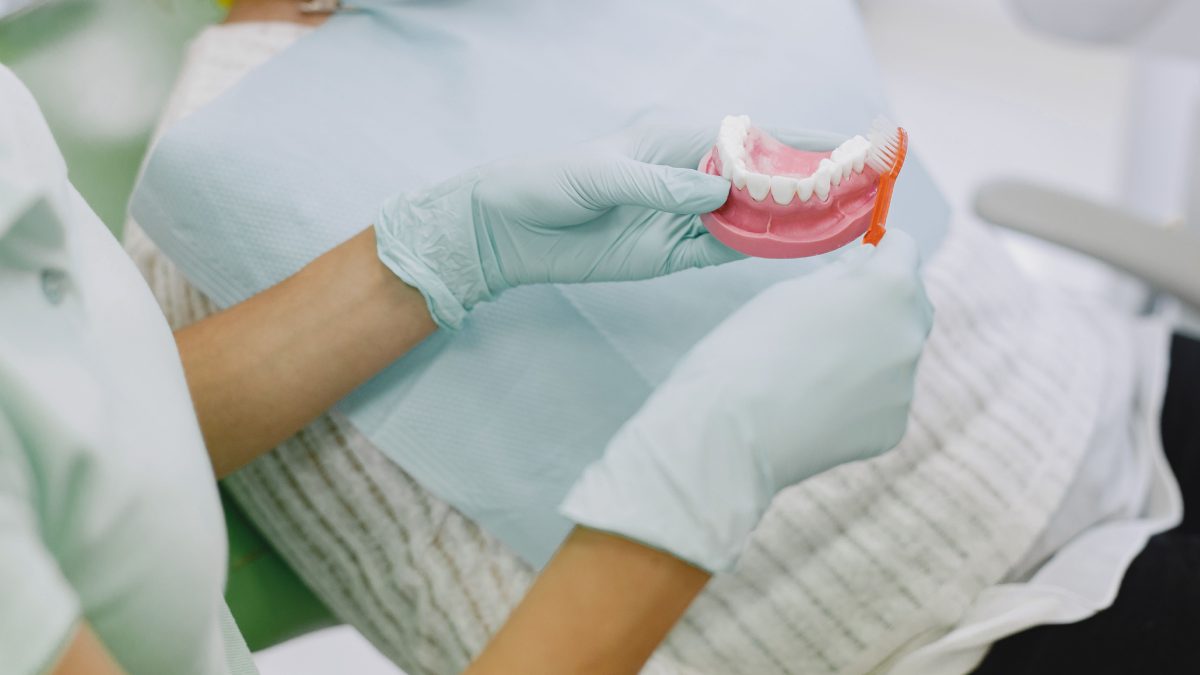 Dentiste qui montre comment nettoyer des dentq avec une brosse à dent.